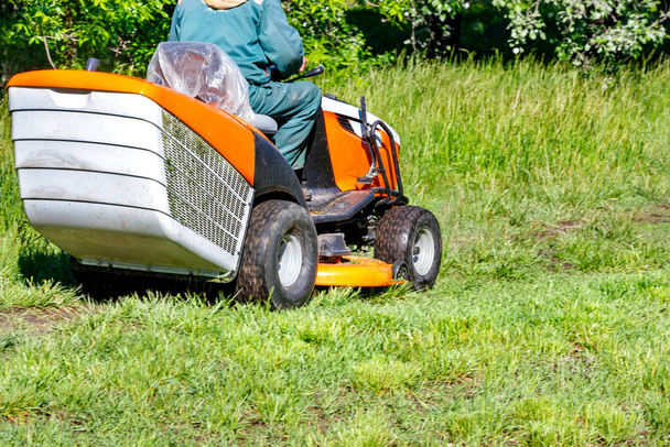 Zadbany park z przyciętym trawnikiem w wyniku pracy ogrodnika z profesjonalną kosiarką traktorów w pogodny słoneczny dzień. - Zdjęcie, obraz