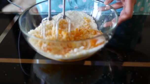 Vrouwelijke chef mengt met de uitgezette mixer de eigeel met suiker in een glazen kom. - Video