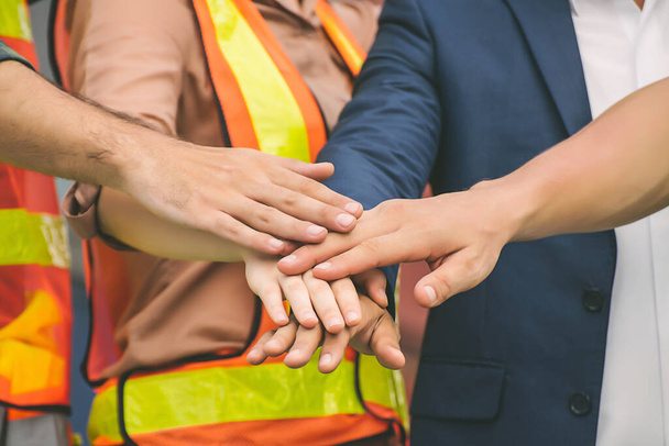Bauarbeiter-Teams geben sich die Klinke in die Hand und arbeiten mit dem Geschäftsmann im blauen Anzug zusammen. - Foto, Bild