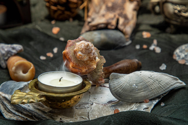 Beauty composition with Burning candle aroma oil lamp and Dry flower petals and Pine cones, Natural pine wood disc, Stones and Shells, Himalayan salt on dark background. Aromatherapy concept. - Фото, зображення