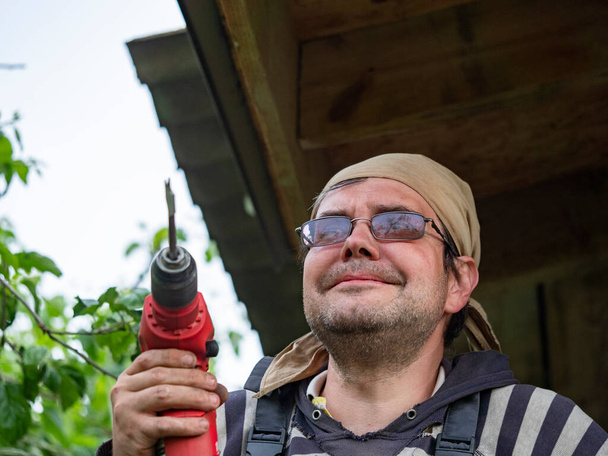 Adult Caucasian man with an electric drill in his hands - Valokuva, kuva