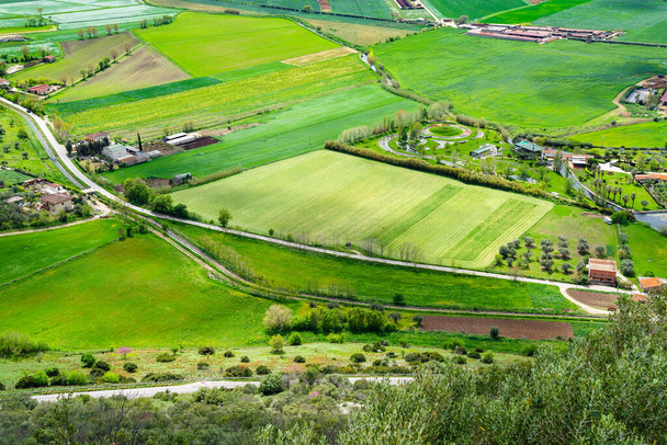 Wspaniały krajobraz południowych Włoch wiosną. Widok z wysokiej góry do zielonej doliny. Pola uprawne, łąki, gospodarstwa rolne, zagrody, drogi, gaje oliwne, krzewy, drzewa - Zdjęcie, obraz