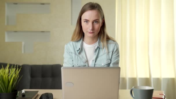 Hermosa mujer joven que trabaja en el ordenador portátil mientras está sentado en la sala de estar - Imágenes, Vídeo
