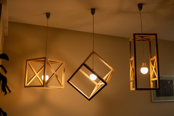 Lámpara de bombillas de techo moderna hecha de marco de madera forma geométrica interior y estilo loft decoración con pared de madera blanca
. - Foto, imagen