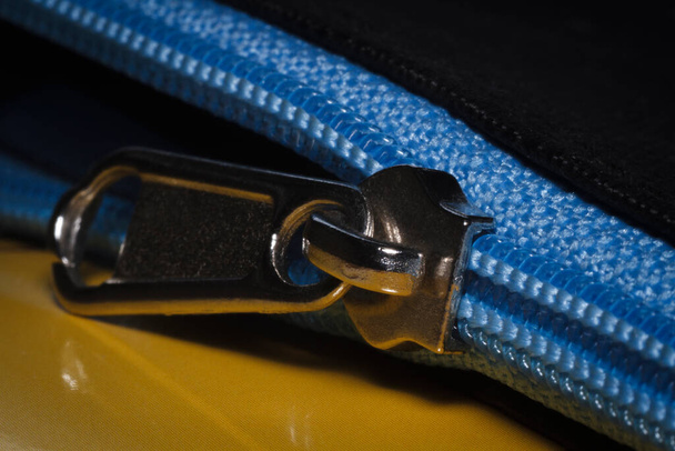 Close-up de um zíper azul na bolsa preta
 - Foto, Imagem