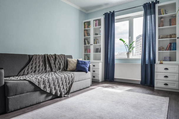 Light cozy teen room with white bookcases,  grey sofa and blue wall - Valokuva, kuva