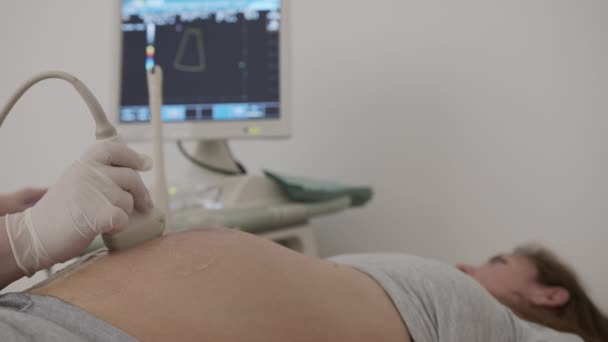 Zwangere vrouw kijkt naar procedure echografie van de baby. Onderzoek van de baby bij echografie. - Video