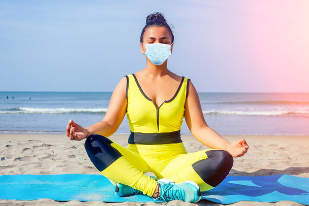 indian woman meditating on sea beach outdoor in medical mask - Фото, изображение