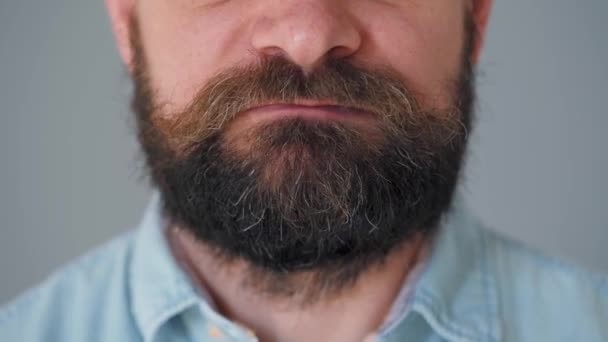 Close-up van een man met een baard die kauwgom kauwt. Man blaast een bel kauwgom - Video