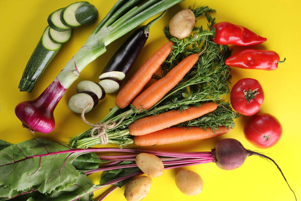 Fresh vegetables. Tomatoes, zucchini, potatoes, carrots, eggplant, beet and peppers on a bright yellow background. Flatlay, top view. Background image, copy space  - Foto, Imagen