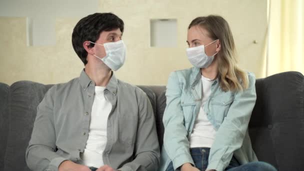 The Covid-19 virus epidemic ends, a woman and a man sitting on a sofa at home take off their surgical masks - Filmati, video