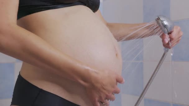 Těhotné ženy hladí její břicho ve sprše. Closeup. - Záběry, video