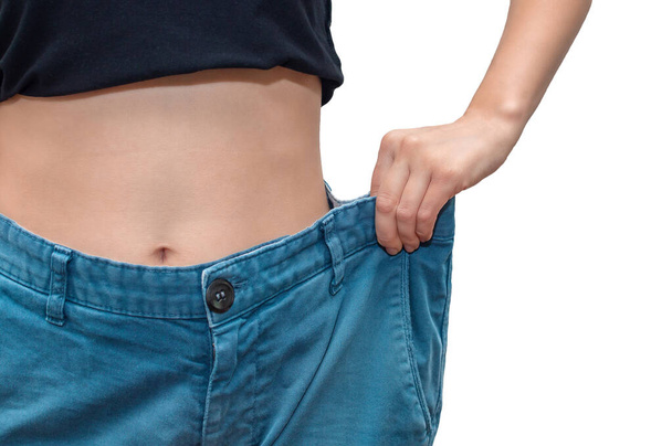 Mujer joven y deportiva mostrando pantalones grandes. El concepto de perder peso y un estilo de vida saludable
. - Foto, Imagen