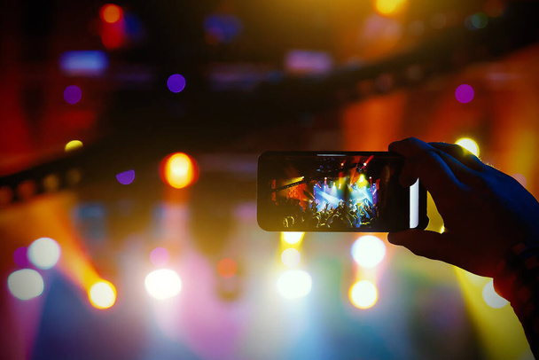 Молодые люди снимают фото или видео концерта на смартфоне
. - Фото, изображение