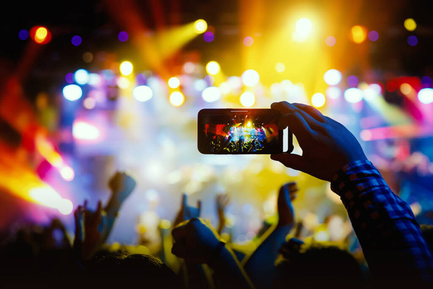 Sziluett kézzel kamera telefon, hogy képeket és videókat élő koncert, show - Fotó, kép