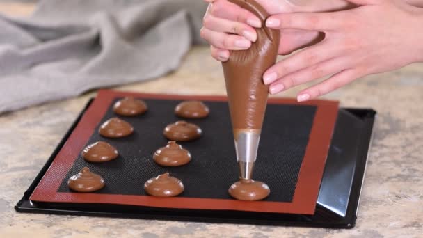 Csokoládé profiterol főzés, női kéz nyomja a tésztát a zsákból a sütőlapra. - Felvétel, videó
