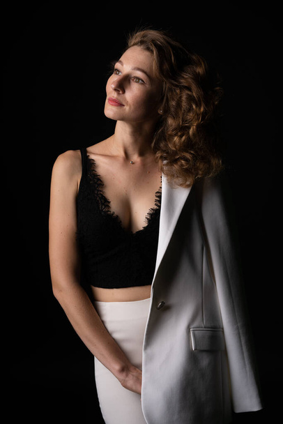Okouzlující žena v bílém obleku na černém pozadí, je elegantní a elegantní - Fotografie, Obrázek