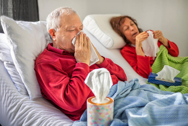 Starsza para leżąca na łóżku i dmuchać w nos, covid 19 i koncepcja grypy z tkanek i koc - Zdjęcie, obraz