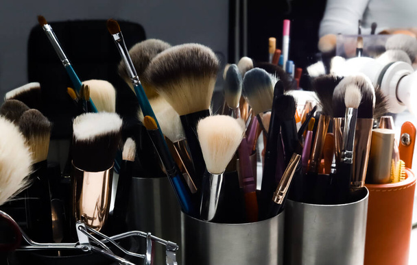 reflection of make up brushes in mirror in metal black can on table in beauty salon close up - Foto, Imagem