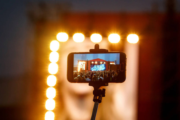 Smartphone op selfie monopod stick. Concertvoorstelling achtergrond - Foto, afbeelding