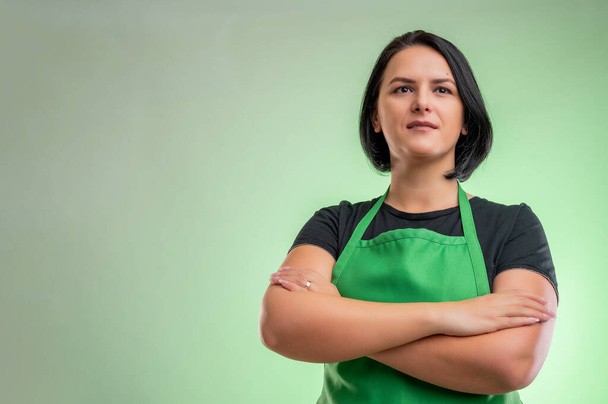 緑のエプロンと黒のTシャツを持つ女性料理人,緑の背景に隔離された自信のヒーローショット - 写真・画像