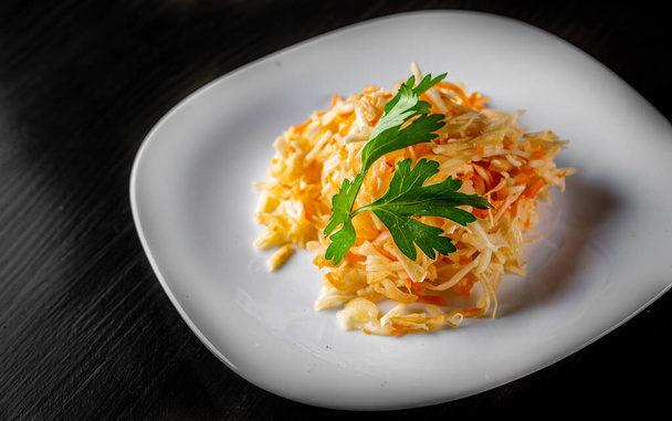 fresh vegetables salad with cabbage and carrot in a white plate on dark wooden table - Foto, immagini