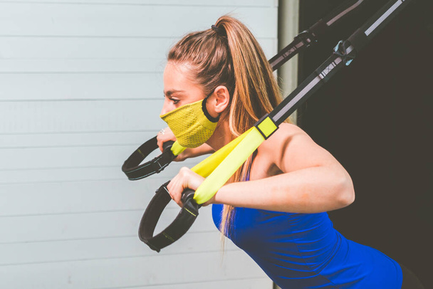 Красива дівчина тренує руки ременями Trx Fitness у спортзалі - жінка тренує грудні плечі грудні трицепси
 - Фото, зображення