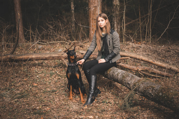Young girl playing with doberman dog in the forest - Foto, imagen