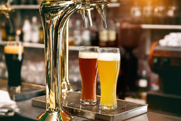Vasos de cerveza ligera y cerveza roja sobre un fondo de pub
. - Foto, Imagen