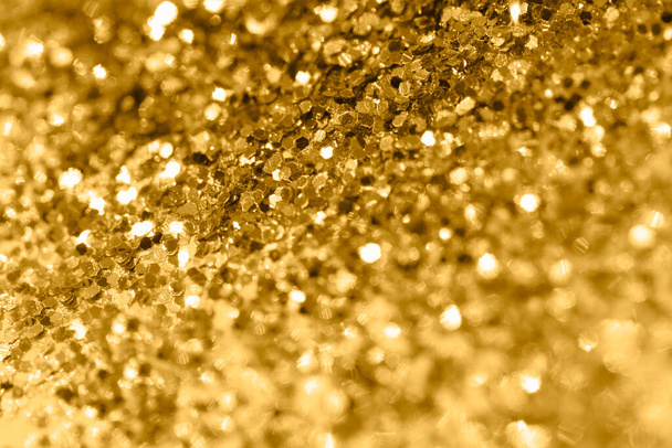 Pile of shining gold pieces seen from above. Top view macro image of sparkling gold dust for backgrounds and textures. Selective focus and shallow depth of field. - Photo, Image