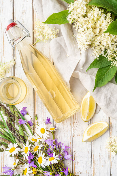 Πεντανόστιμο υγιεινό δροσιστικό ρόφημα, γλυκό σιρόπι Elderflower ή εγκάρδιο σε γυάλινο μπουκάλι σε ρουστίκ ξύλινο φόντο - Φωτογραφία, εικόνα