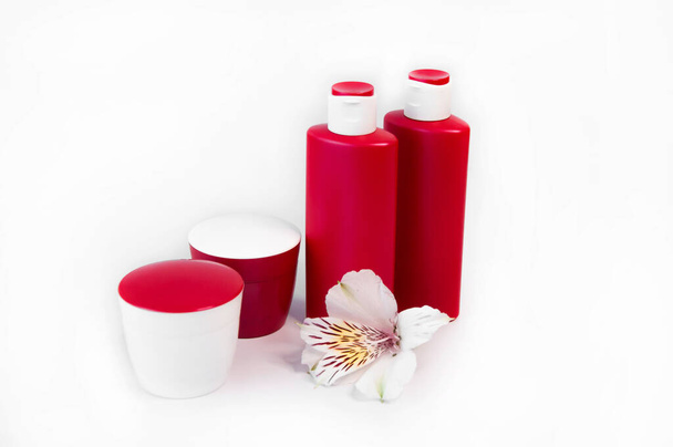 Kosmetikprodukte auf weißem Hintergrund. Rote Flaschen und Gläser, Elch, Tonikum, Sahne. Kopierraum für Text - Foto, Bild