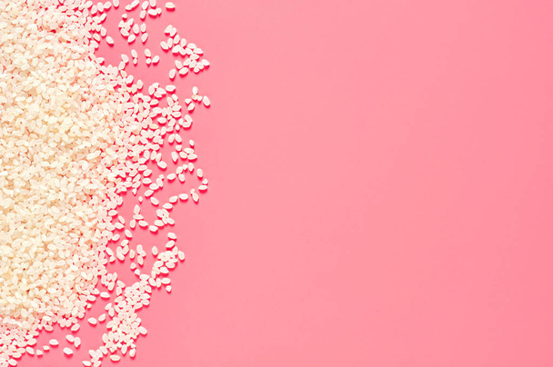 Scattered grain of white rice on pink background. Copy space. Top view - Фото, изображение