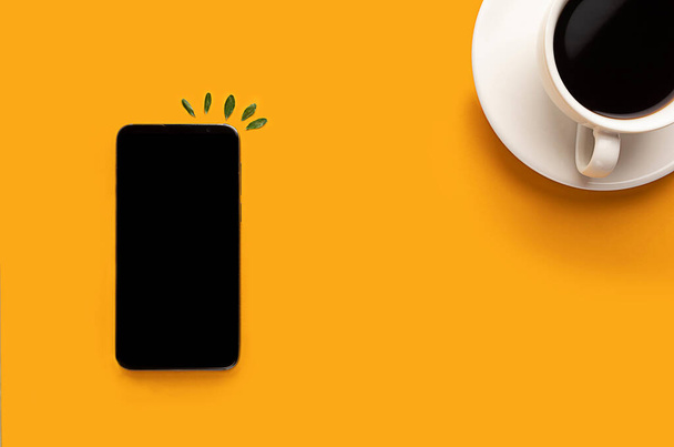 filiżanka kawy i smartfona, telefon na żółtym tle z miejscem do kopiowania. Blogger, poranna koncepcja śniadaniowa - Zdjęcie, obraz