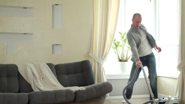 Man playing on vacuum cleaner like on guitar, having fun during house cleaning - Кадри, відео