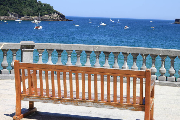 скамейка для сидения с видом на залив Доностия Сан-Себастьян в Стране Басков рядом со знаменитым пляжем Ла Конча
 - Фото, изображение