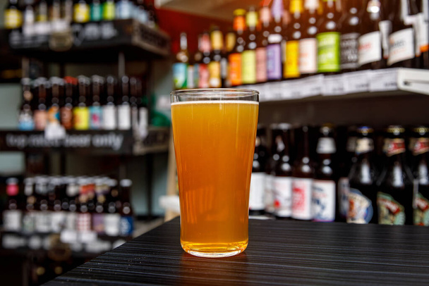 Un vaso de cerveza artesanal en el bar. Surtido de botellas sobre un fondo borroso
 - Foto, Imagen