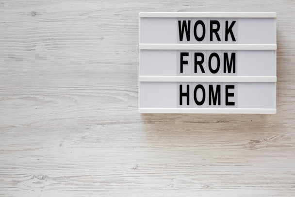"Work from Home" steht auf einem modernen Brett auf weißem Holzgrund, Draufsicht. Über Kopf, von oben, flach liegend. Raum für Text. - Foto, Bild