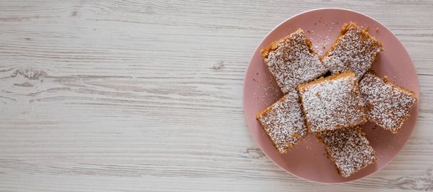 Hausgemachter leckerer Apfelmus-Kuchen auf einem rosa Teller auf weißem Holzhintergrund, Draufsicht. Flach liegend, über Kopf, von oben. Raum für Text. - Foto, Bild