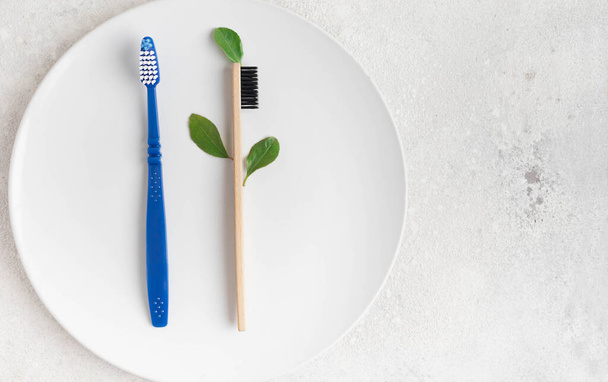 Cepillo de dientes de bambú ecológico natural y cepillo de dientes de plástico sobre un fondo colorido, disposición plana, cero residuos, sin concepto de plástico. Tú eliges. Comparación de cepillo de bambú ecológico y cepillo de plástico
 - Foto, imagen