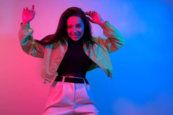 The brunette dances in neon, the dancer in red-blue. Hip hop girl, party, smile. - Photo, Image