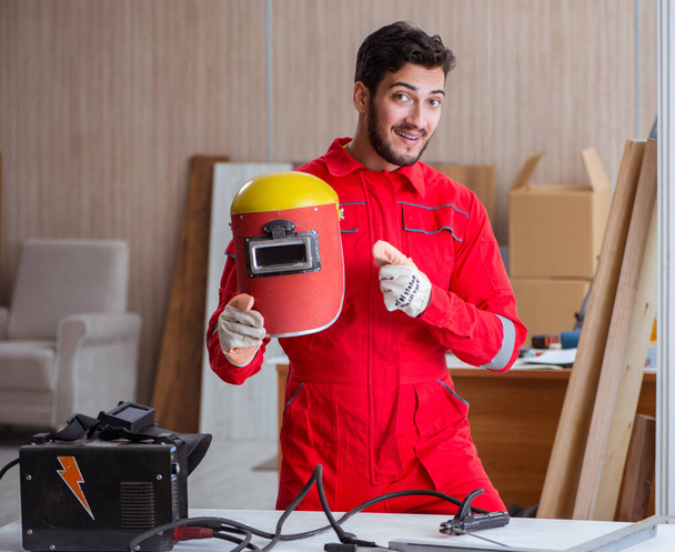 Молодой ремонтник со сварочным электродом и шлемовым сварщиком - Фото, изображение