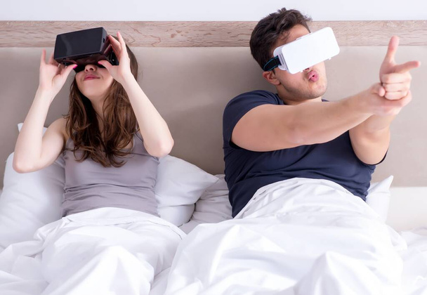Wife and husband with virtual reality goggles in the bed - 写真・画像