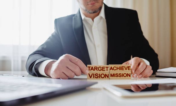 goal achievement concept. man stacks wooden blocks with the words Mission, Vision, Target and Achieve - Foto, afbeelding