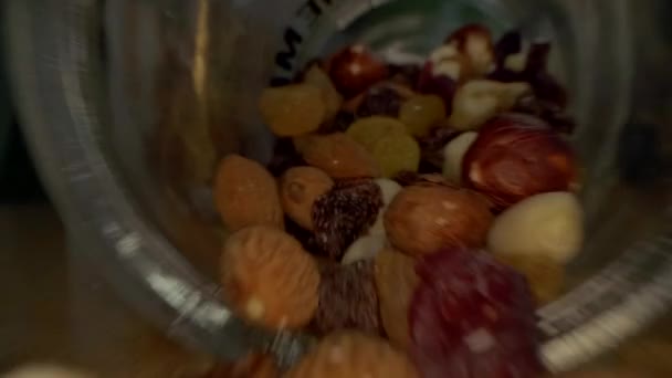 Macro view of the nuts, seeds and dried fruits in a glass jar and on a wooden table - Video, Çekim