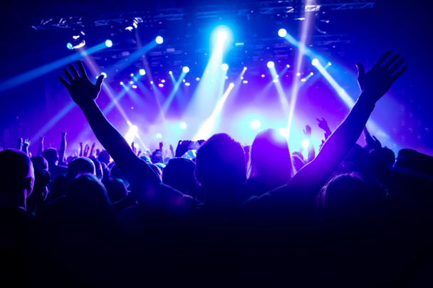 Silhouette dell'uomo con le mani alzate sul concerto di musica. - Foto, immagini