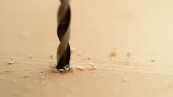 MACRO: Houtspaanders en zaagsel vliegen van een metalen boortje in een plank. - Video