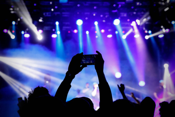 Κινηματογραφώντας μια συναυλία στην κάμερα του κινητού τηλεφώνου, μπλε φως της σκηνής - Φωτογραφία, εικόνα