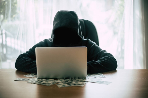 Хакер перед своим компьютером с банкнотой в долларах
. - Фото, изображение