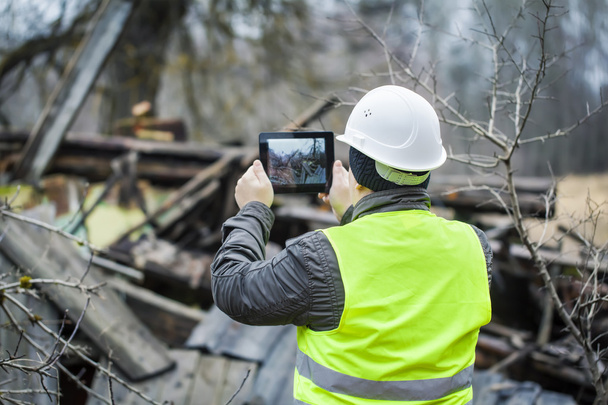 Інспектор з планшетом біля зруйнованої будівлі
 - Фото, зображення